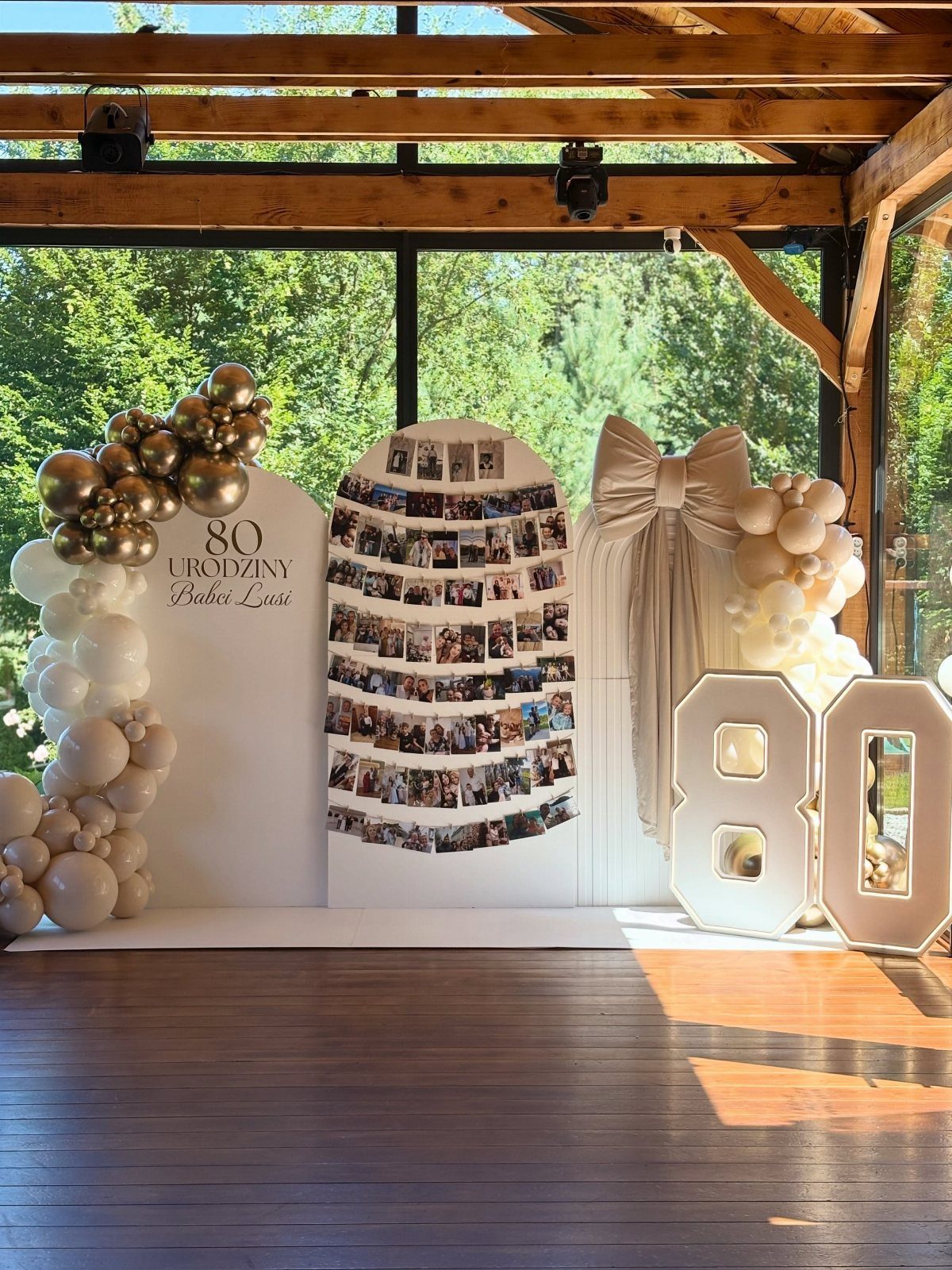 Birthday party backdrop with a photo memory wall, gold balloons, and glowing 80 numbers.