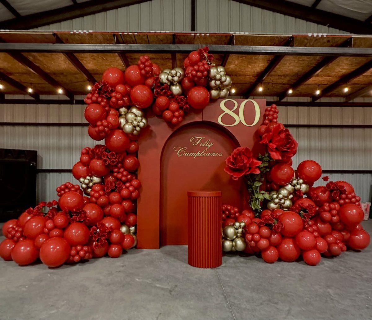 Red and gold balloon arch with a gold 80 for a birthday celebration