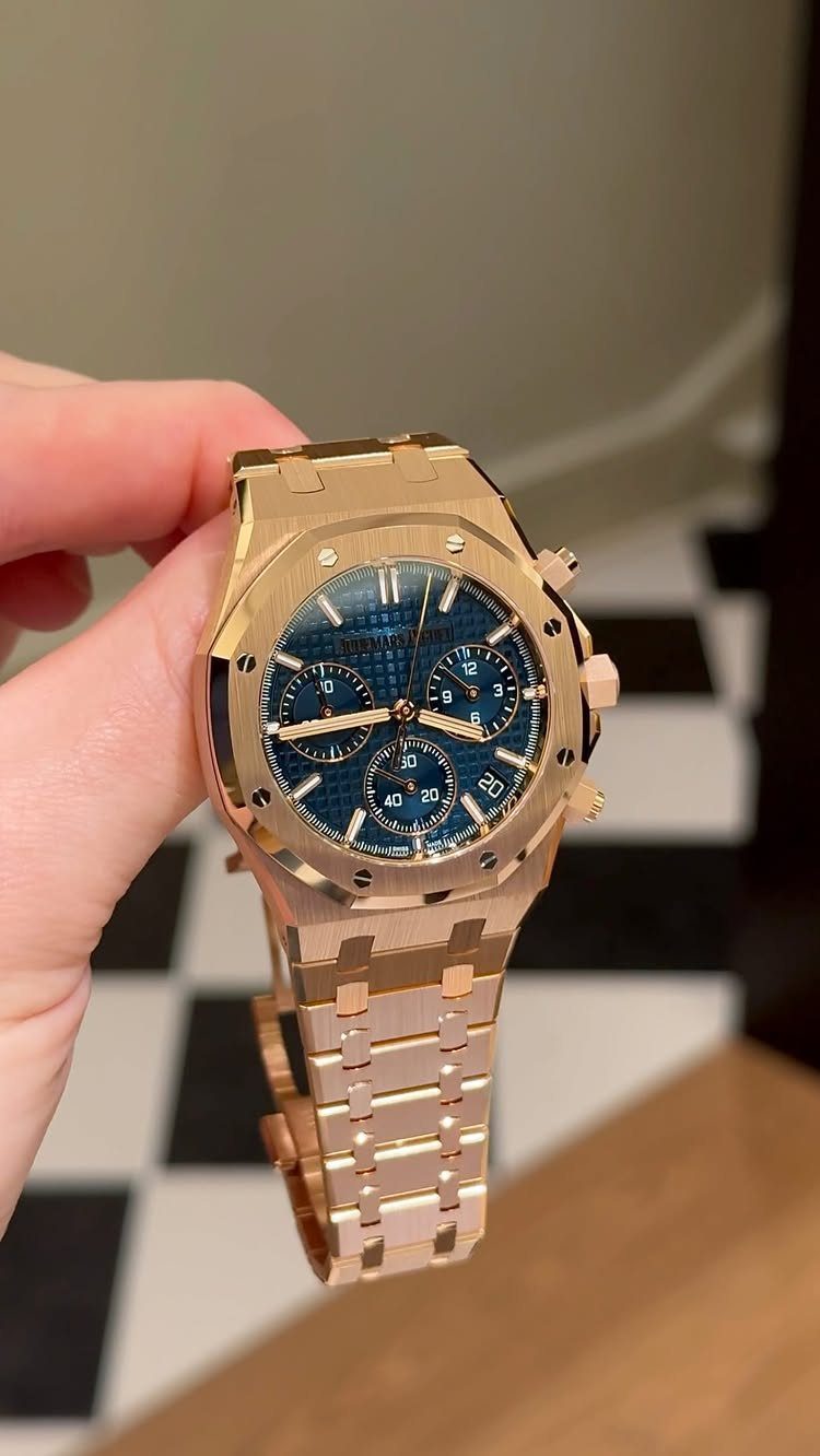 Gold luxury wristwatch with a blue dial held by a person's hand