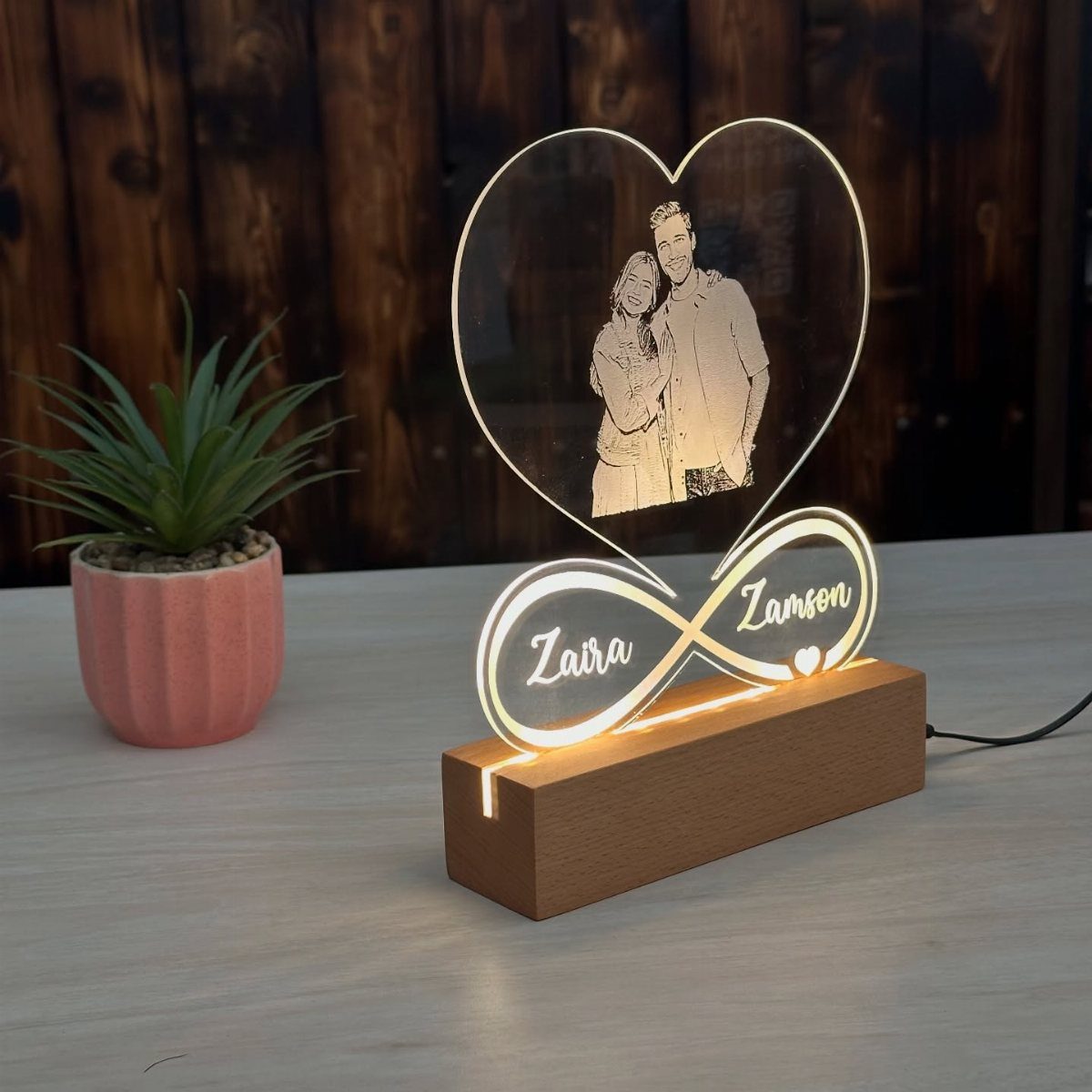 Engraved acrylic heart lamp with a couple and names on a wooden base.
