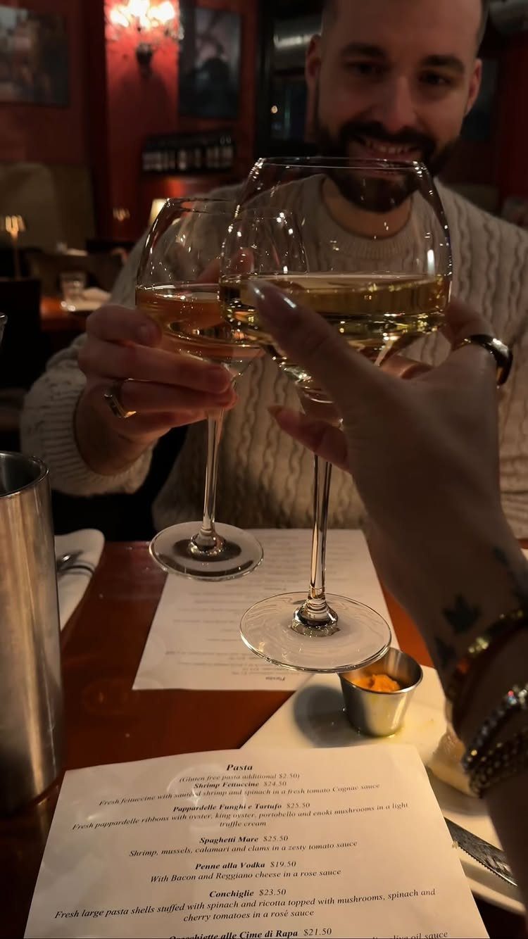 Couple clinking white wine glasses during a romantic dinner date at a restaurant