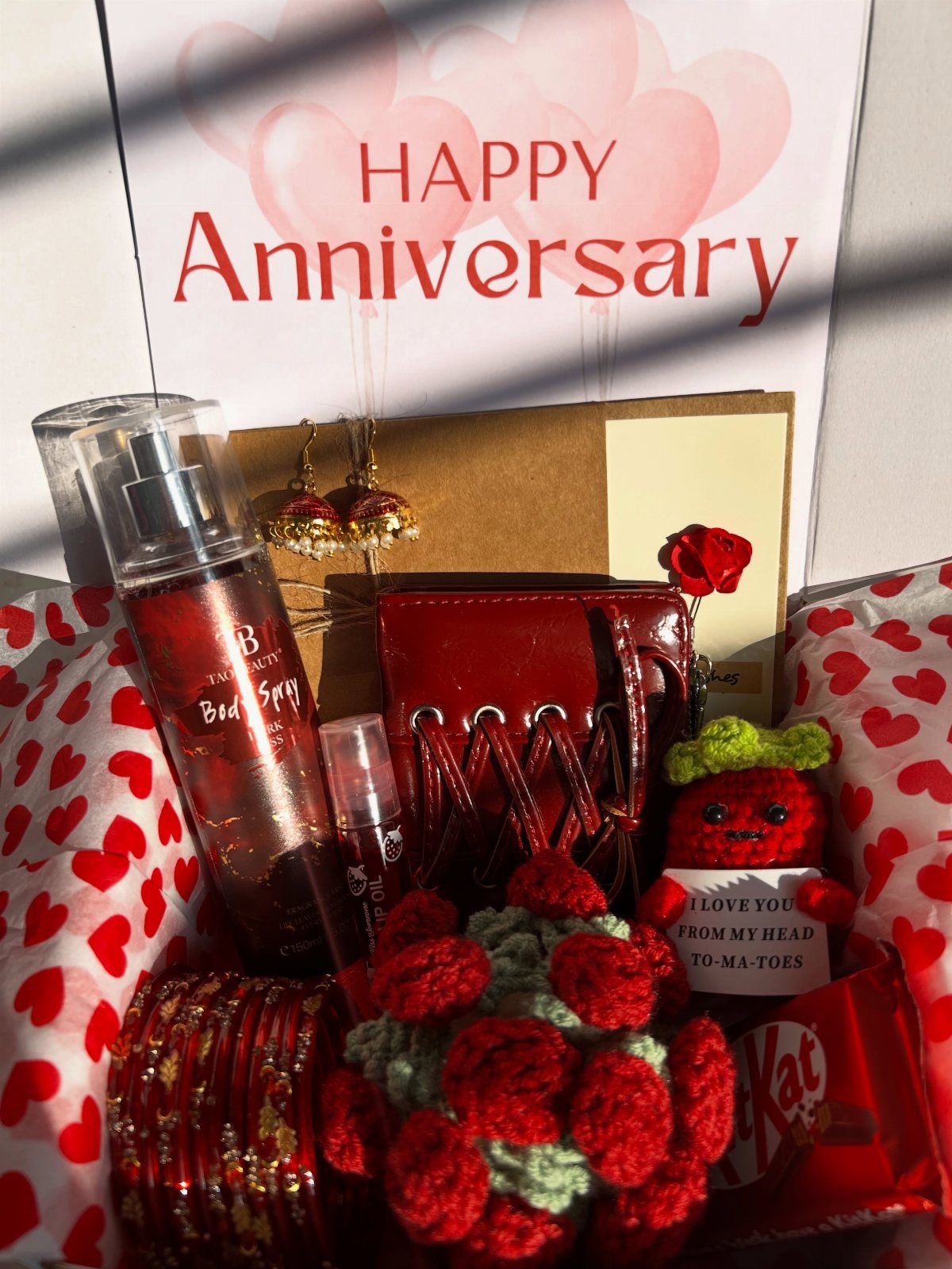 Red anniversary gift basket with body spray, purse, jewelry, and a celebratory card.