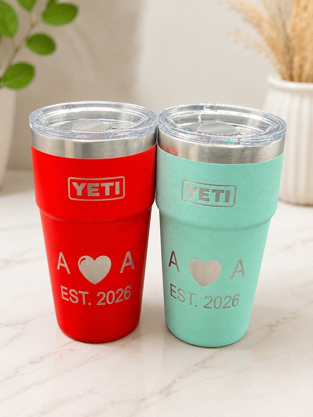 Two engraved Yeti tumblers in red and blue with a heart and date.
