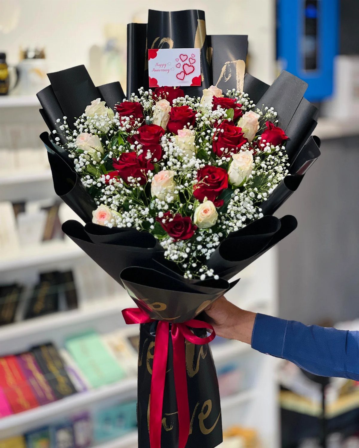 Large bouquet of red and white roses wrapped in black paper with red ribbon
