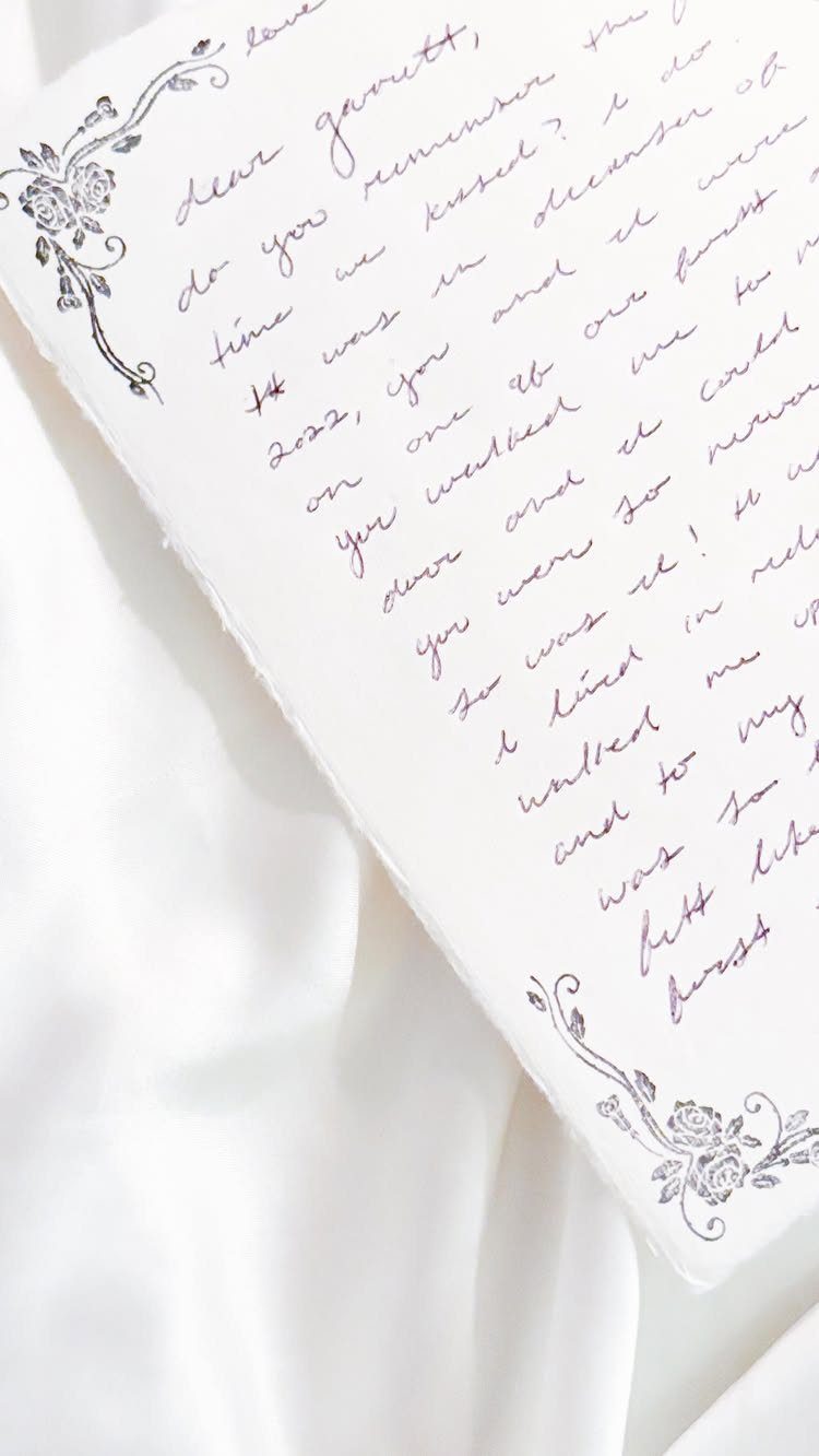Handwritten cursive love letter on white paper with decorative floral corner borders