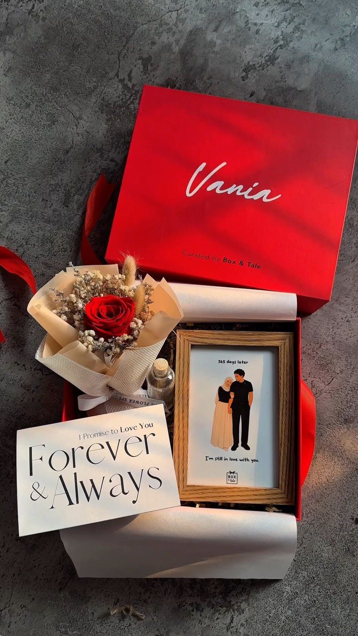 Red gift box with a rose, framed couple illustration, and romantic card.