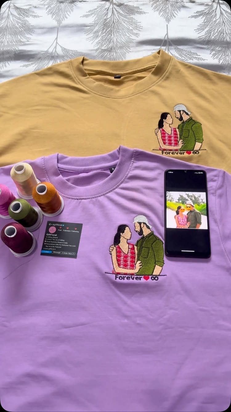 Two t-shirts with embroidered couple illustrations next to a smartphone and embroidery threads.