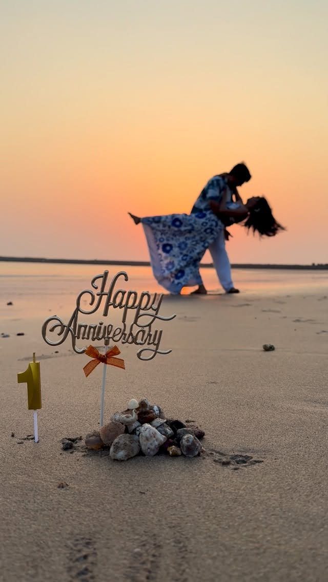 Couple dancing on a beach at sunset with anniversary decorations in the foreground