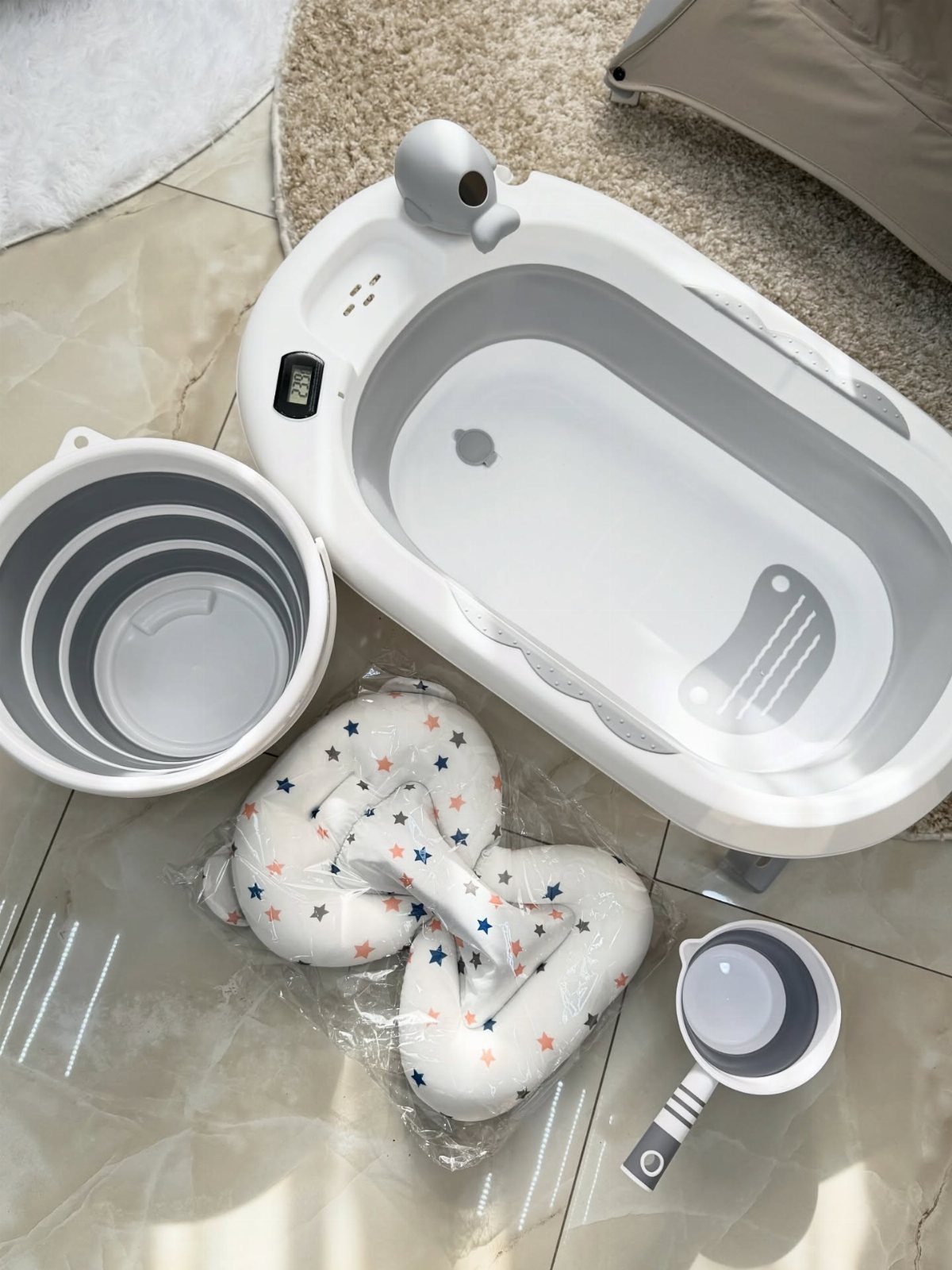 White baby bathtub with matching bucket, star-patterned support cushion, and rinsing cup.