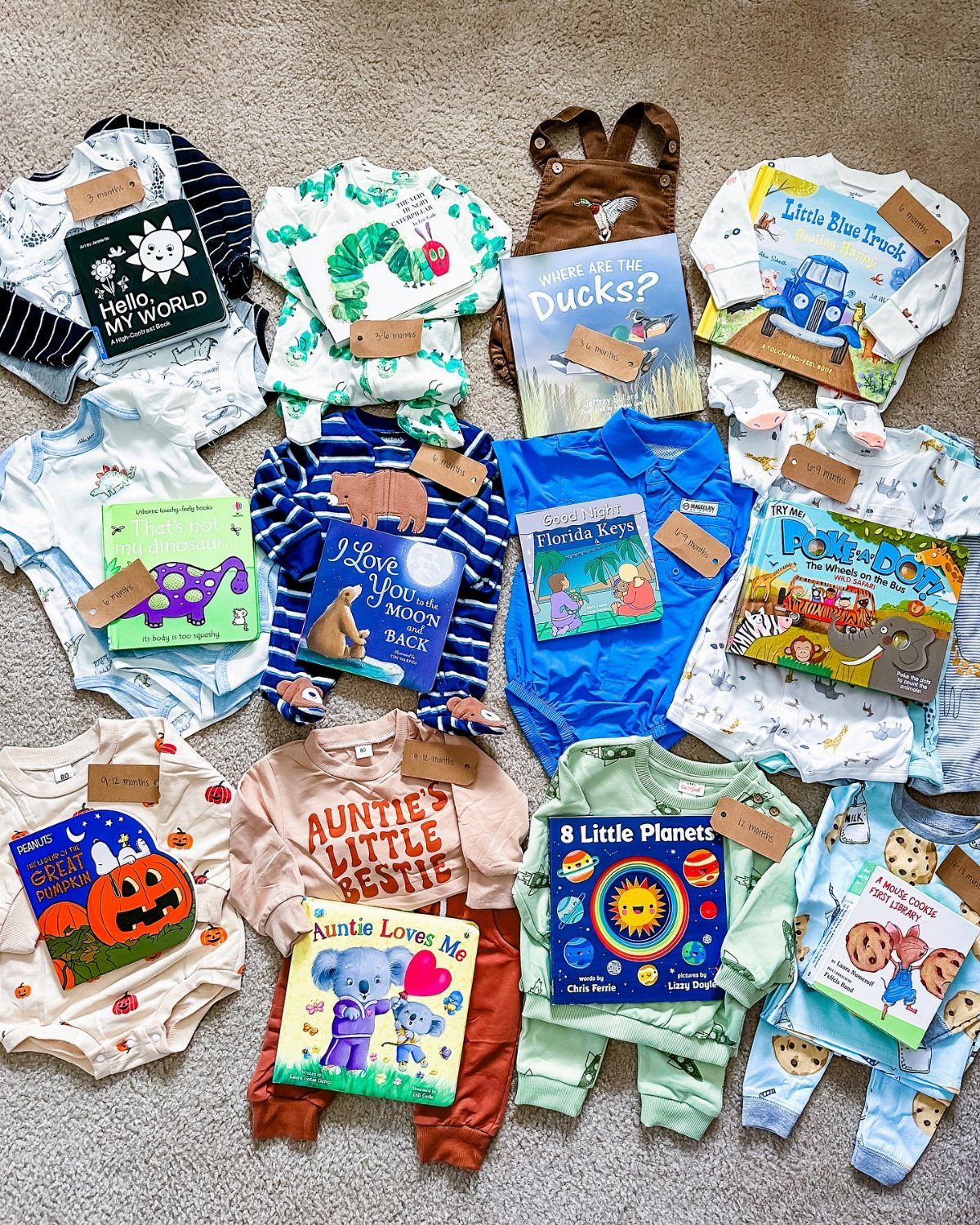 Baby clothes and children's board books paired together on a grey carpet.