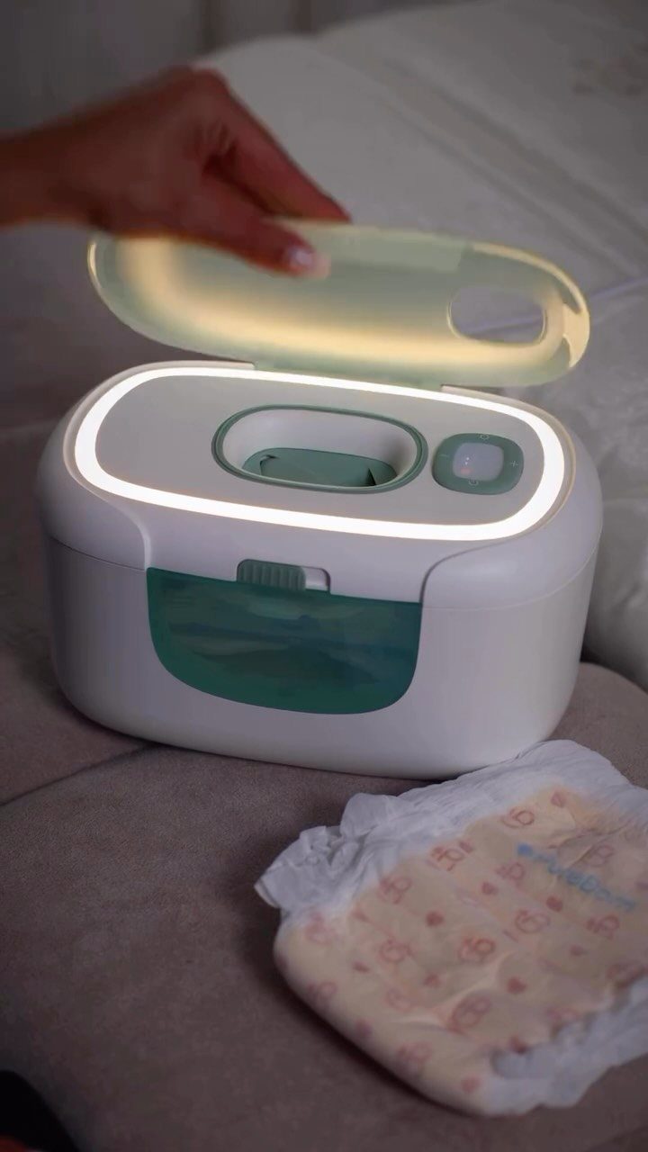 White and teal baby wipes warmer with glowing lid and nearby wipes pack.