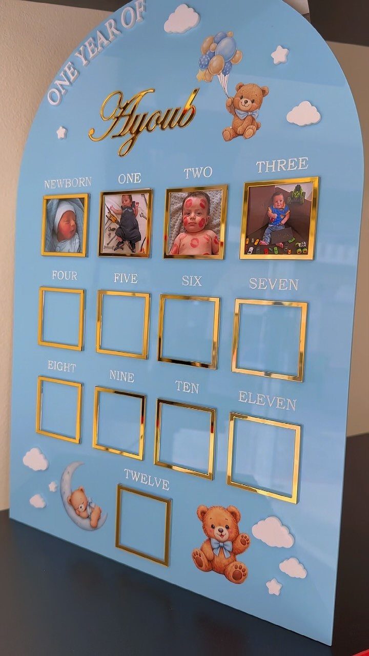 Blue arched baby photo frame with gold borders and teddy bear decorations.