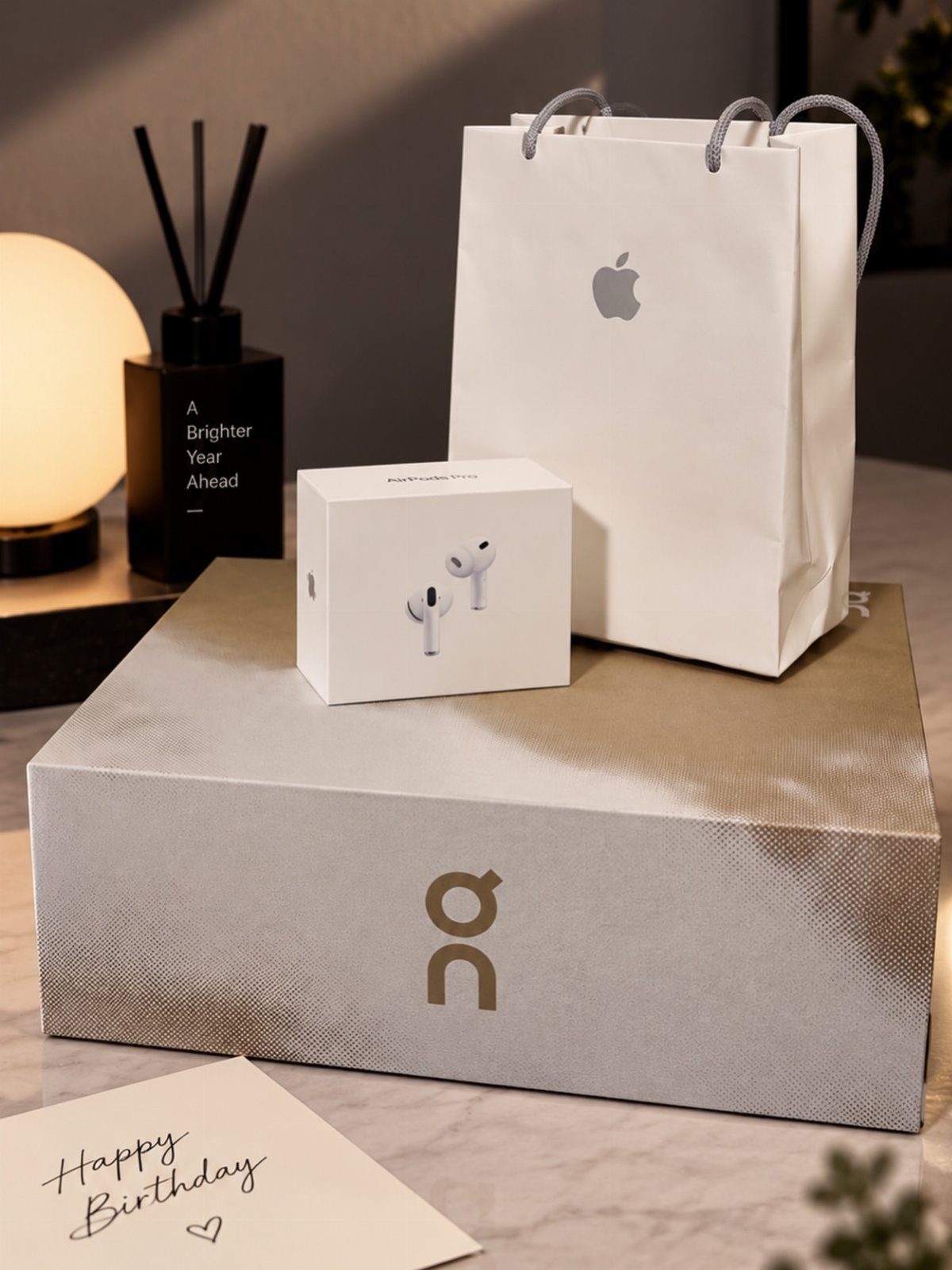 Apple AirPods box and Apple shopping bag on a grey shoe box with birthday card