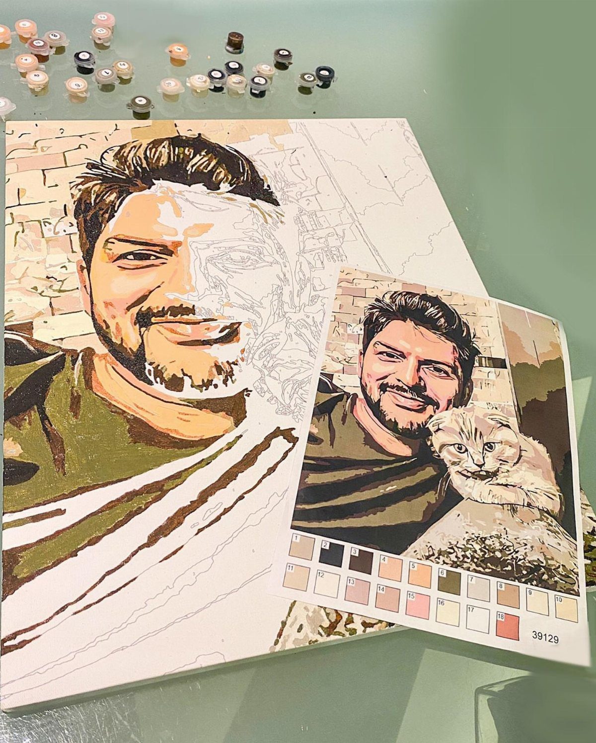 Partially painted custom paint by numbers canvas of a man with reference photo.