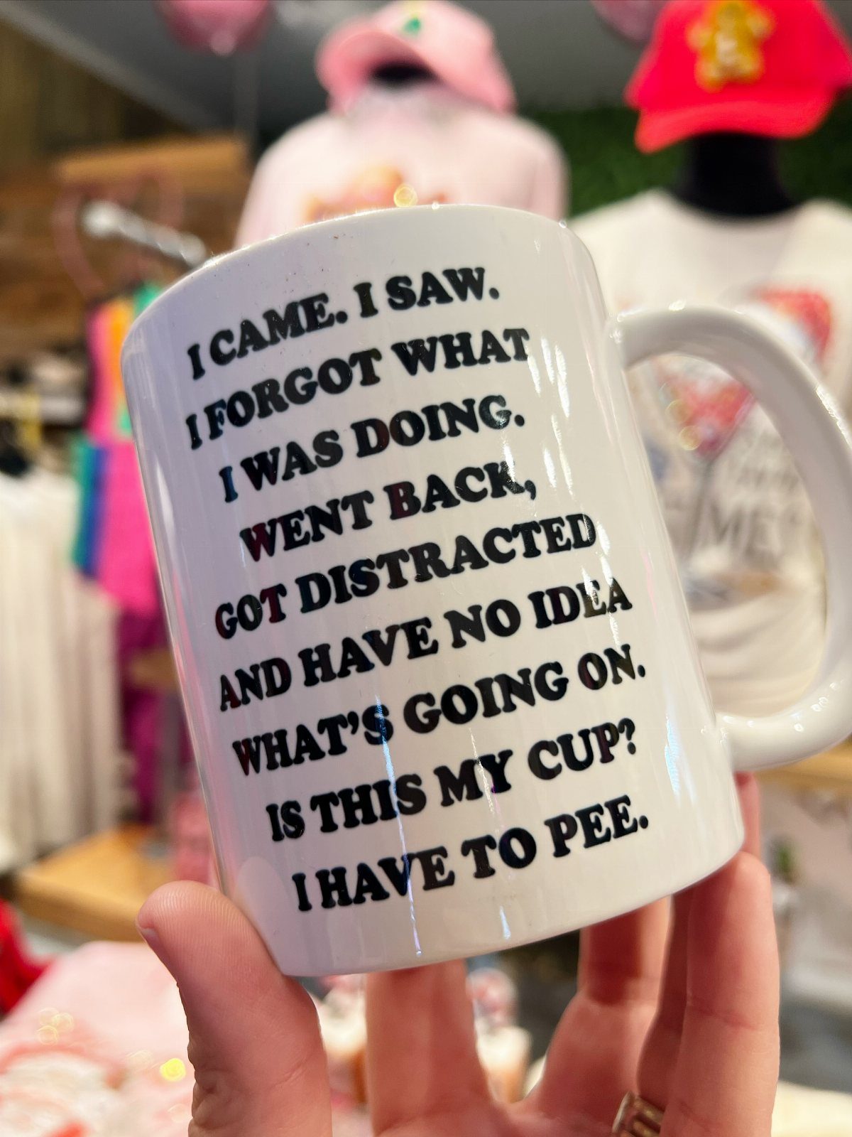 White ceramic coffee mug with funny black text held by a person's hand.