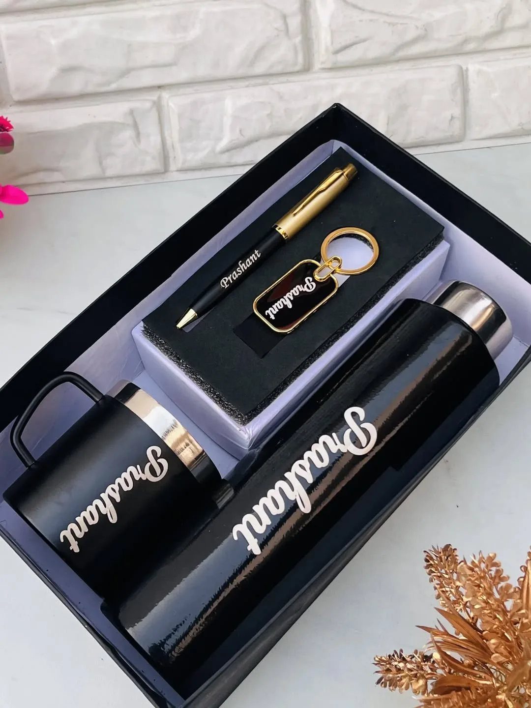 Personalized black gift set with thermos, mug, pen, and keychain engraved with Prashant.