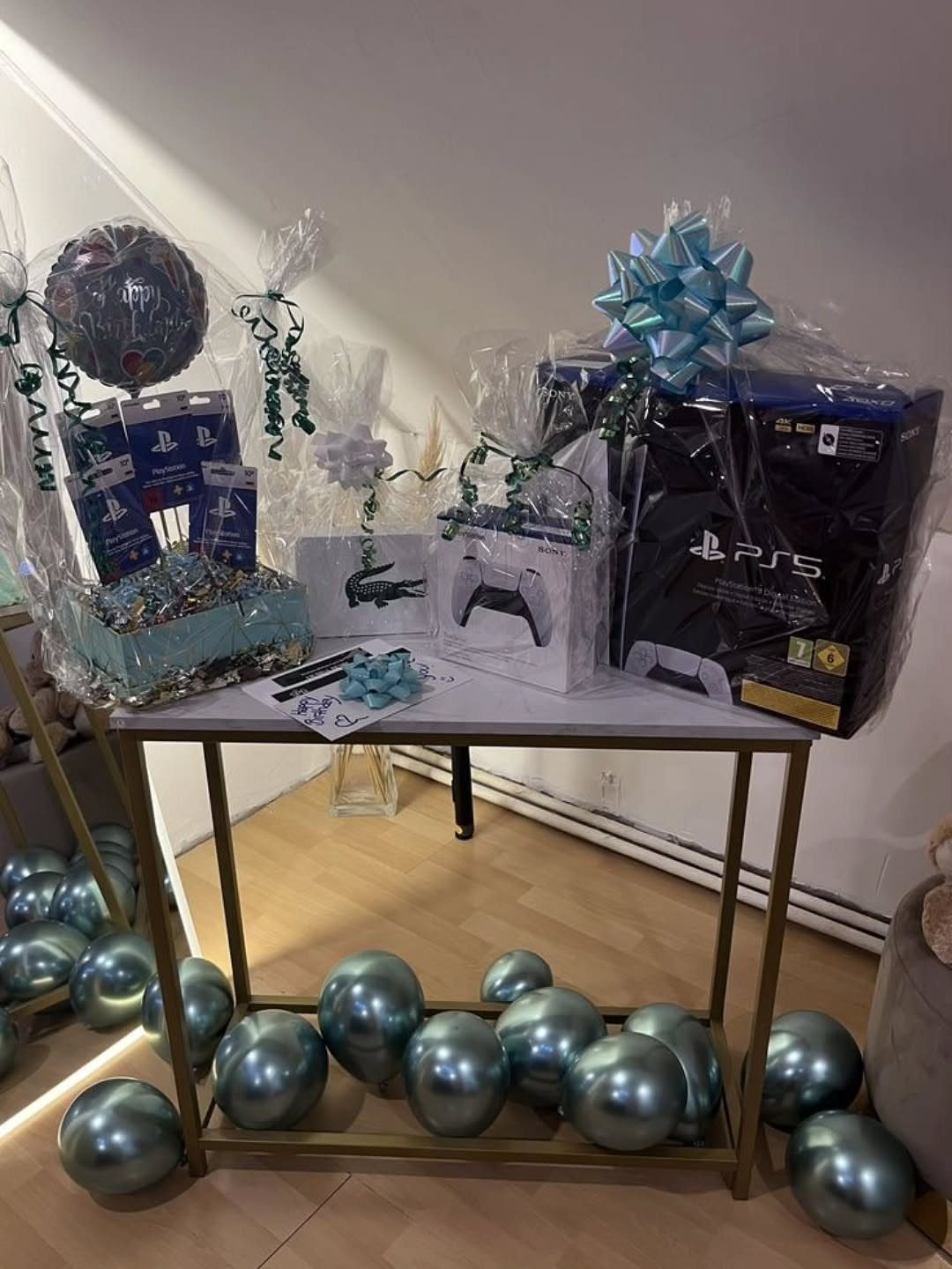 PlayStation 5 console and controller as gifts on a table with blue balloons.