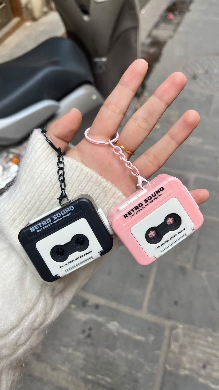 Two cassette tape keychains in black and pink held in a hand.