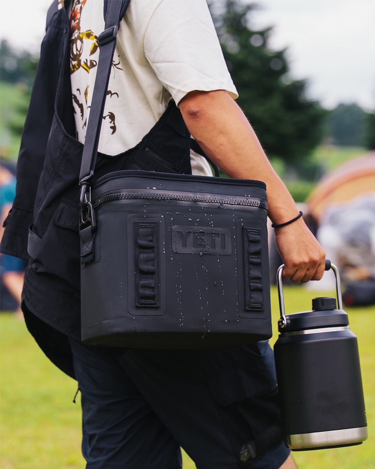 Black YETI Hopper Flip portable cooler bag carried by a person outdoors.