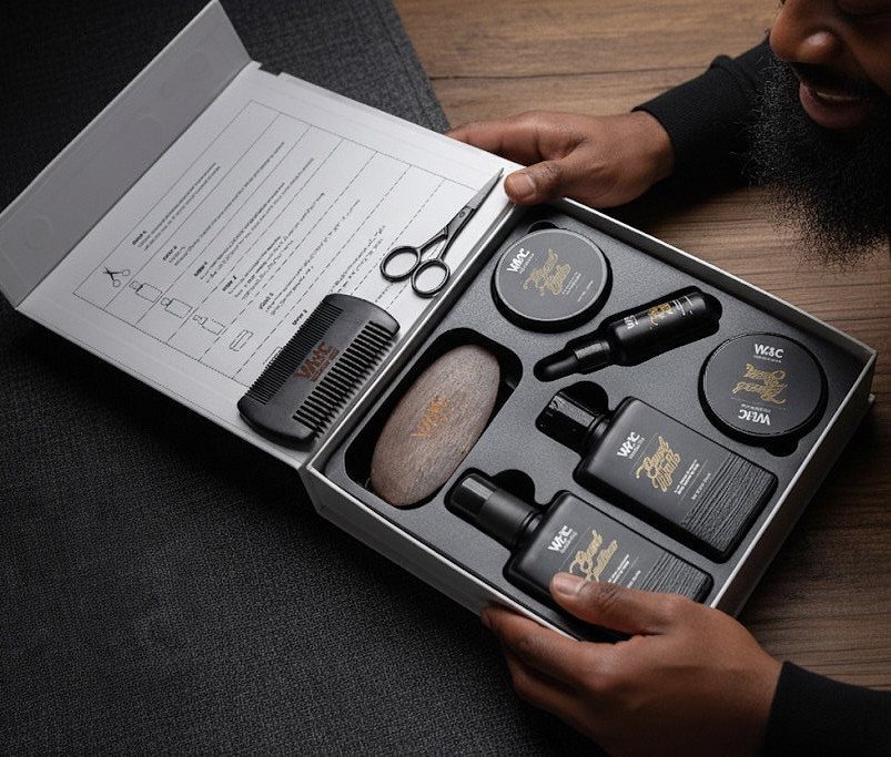 Beard grooming kit in a black box with oils, balms, and grooming tools.