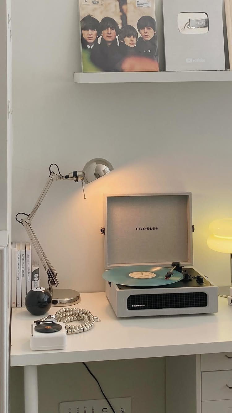 Silver Crosley turntable playing a teal vinyl record on a white desk