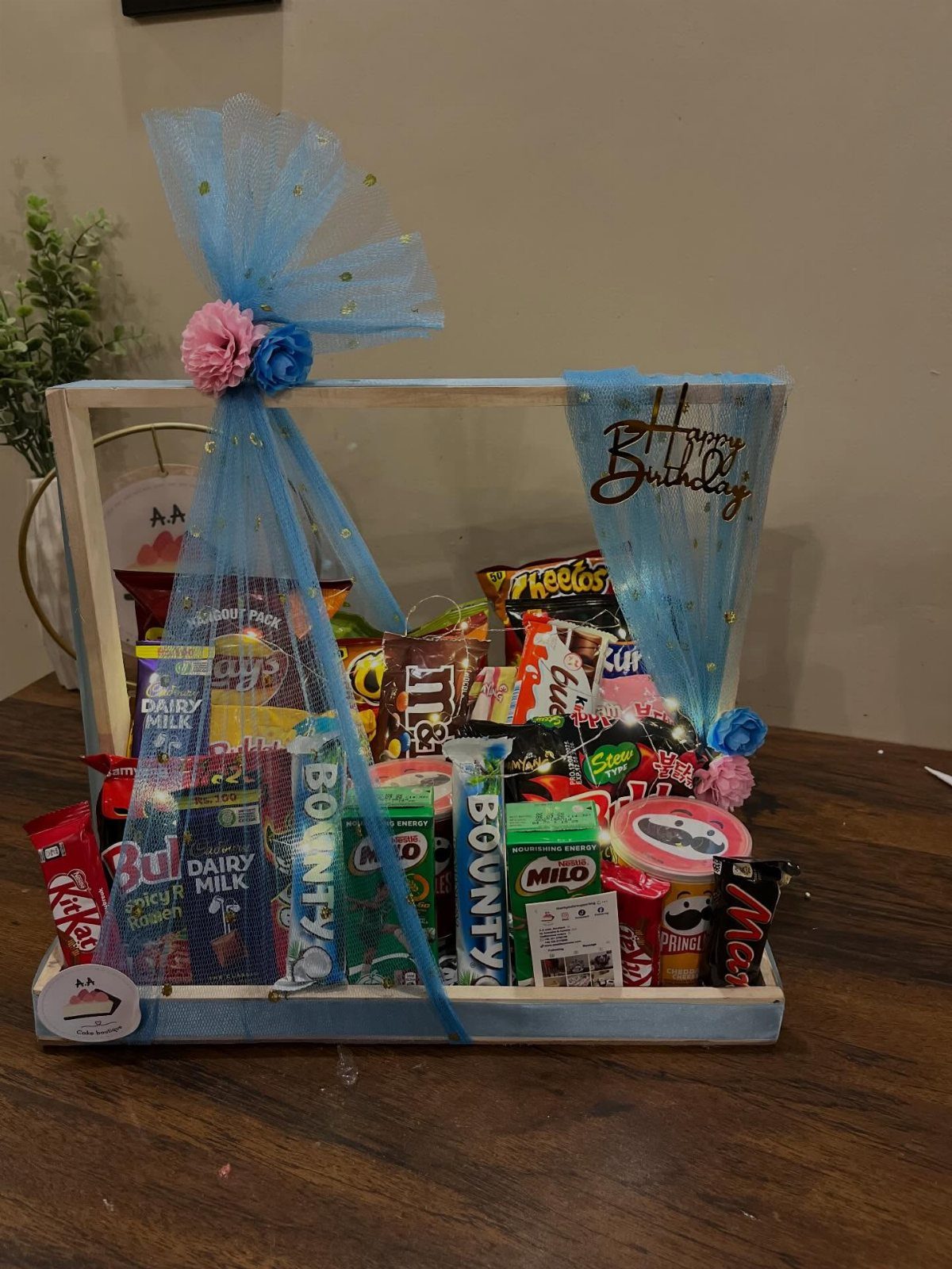 Candy gift crate with blue tulle bow and Happy Birthday topper on table