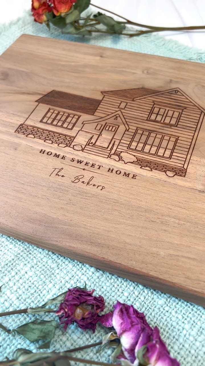 Engraved wooden cutting board featuring a house illustration and personalized family name.