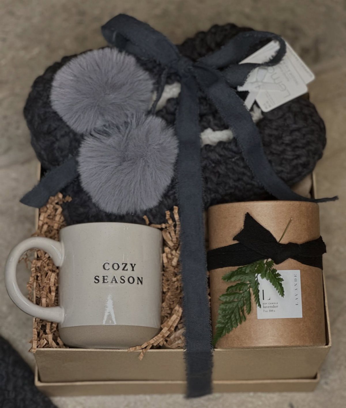 Gift box with a cozy mug, knit slippers, and a wrapped candle.