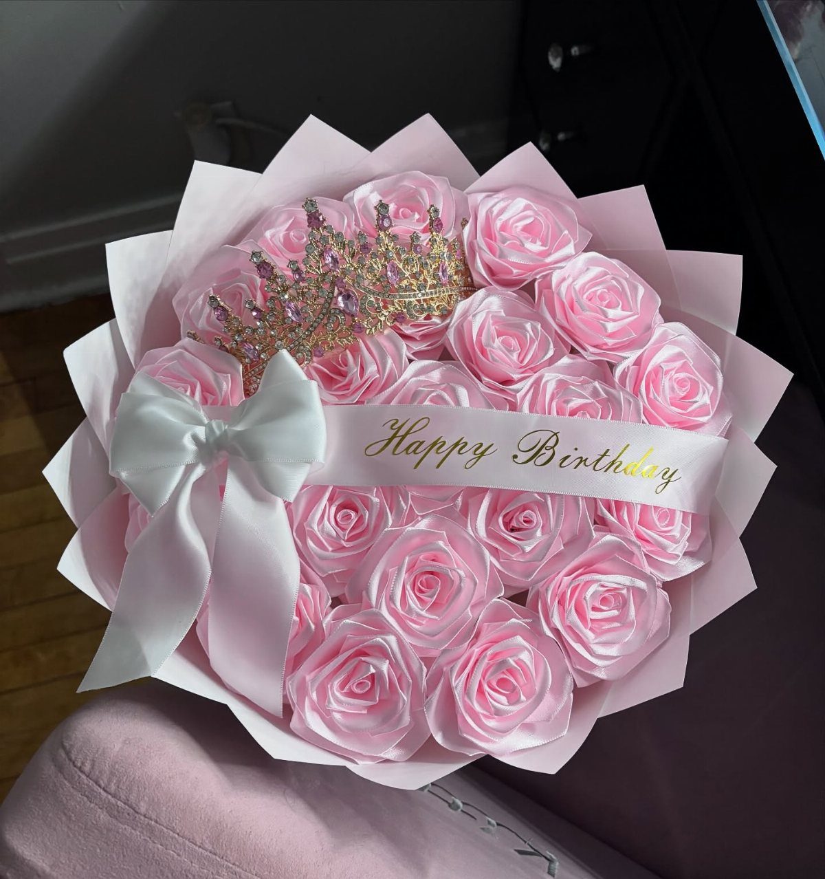 Pink artificial rose bouquet with a gold crown and Happy Birthday ribbon.