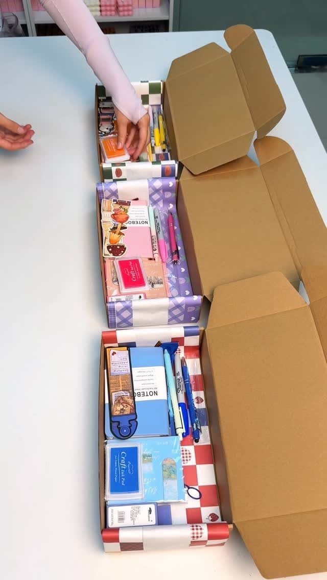 Three open gift boxes filled with stationery, notebooks, and pens on a table