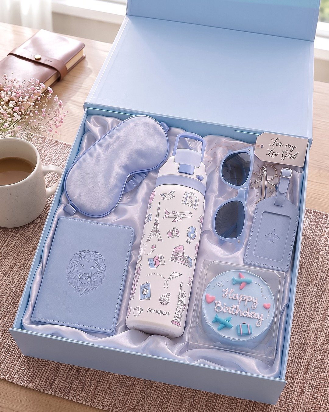 Light blue travel-themed birthday gift set in a box with a small cake.