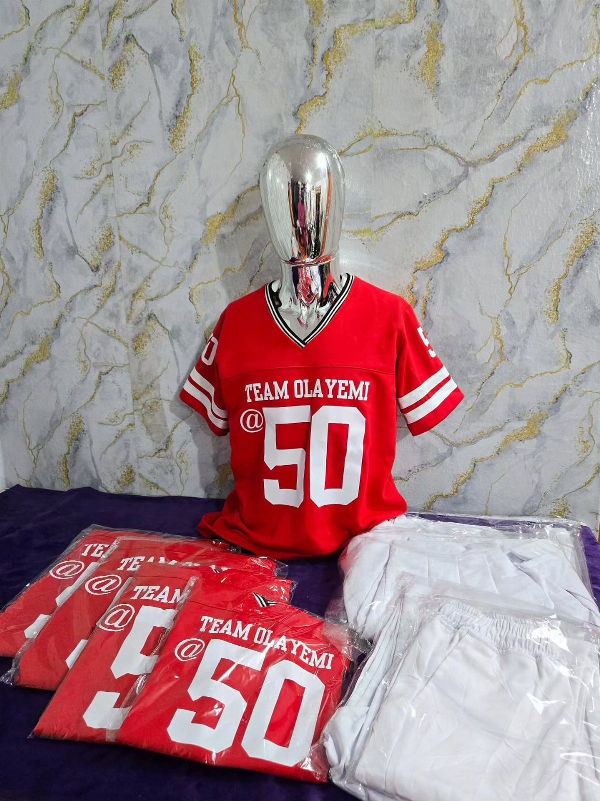 Red custom sports jersey with number 50 on a silver mannequin and packaged sets.