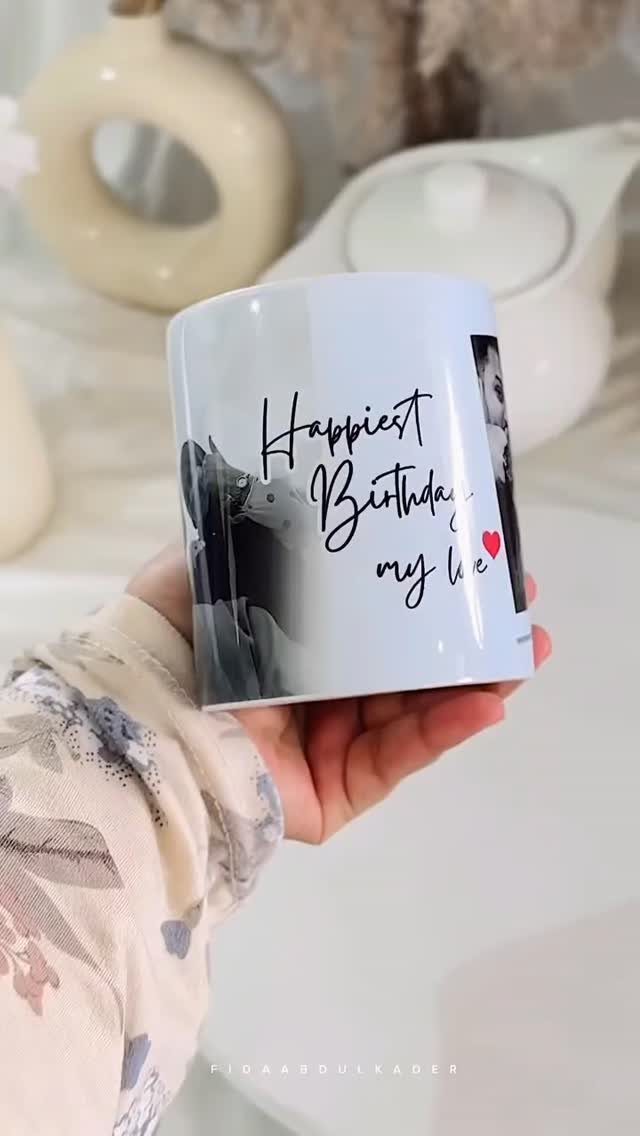 Personalized white coffee mug with birthday message and photo held in a hand.