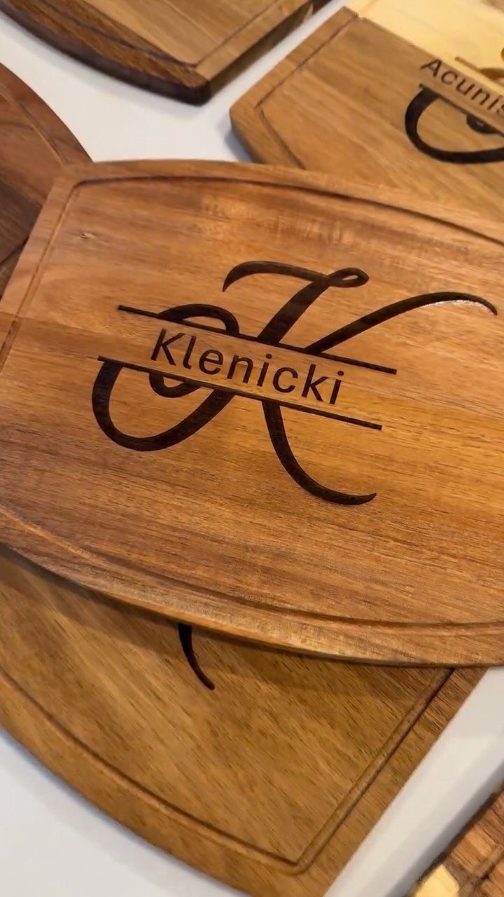 Wooden cutting boards with engraved names and initials on a white surface.