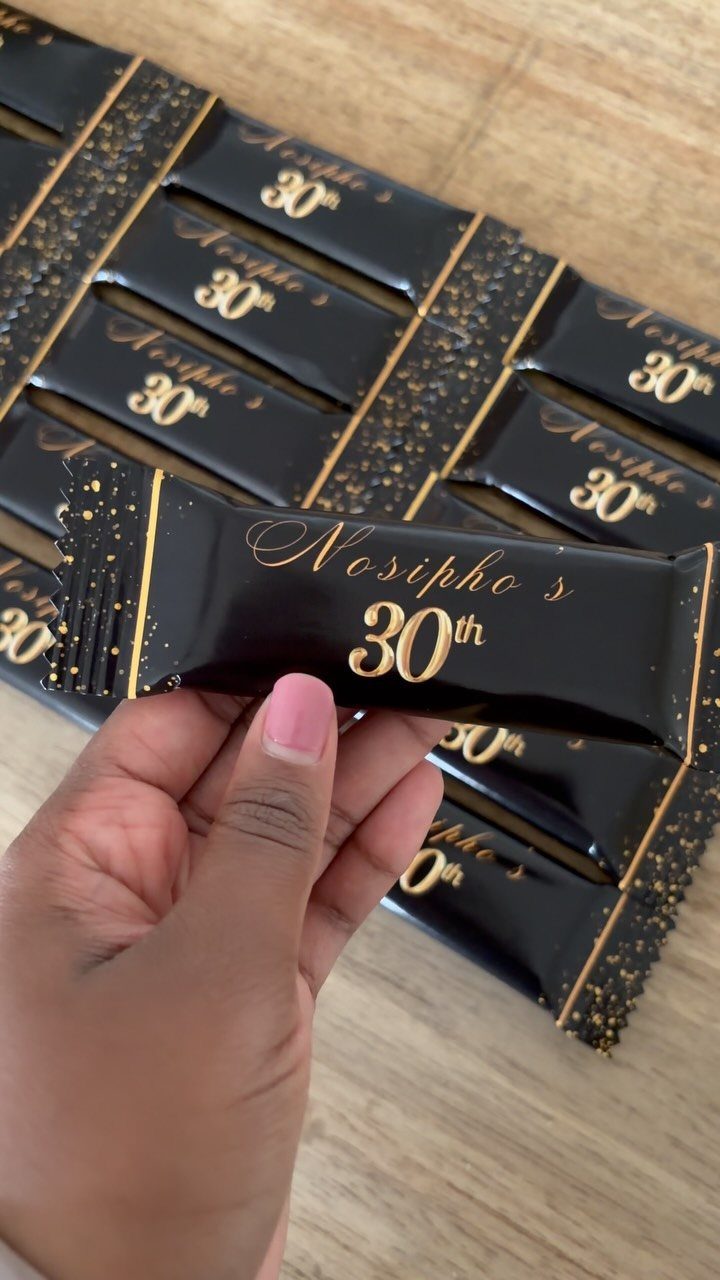 Hand holding a black and gold chocolate bar wrapper for a 30th birthday.