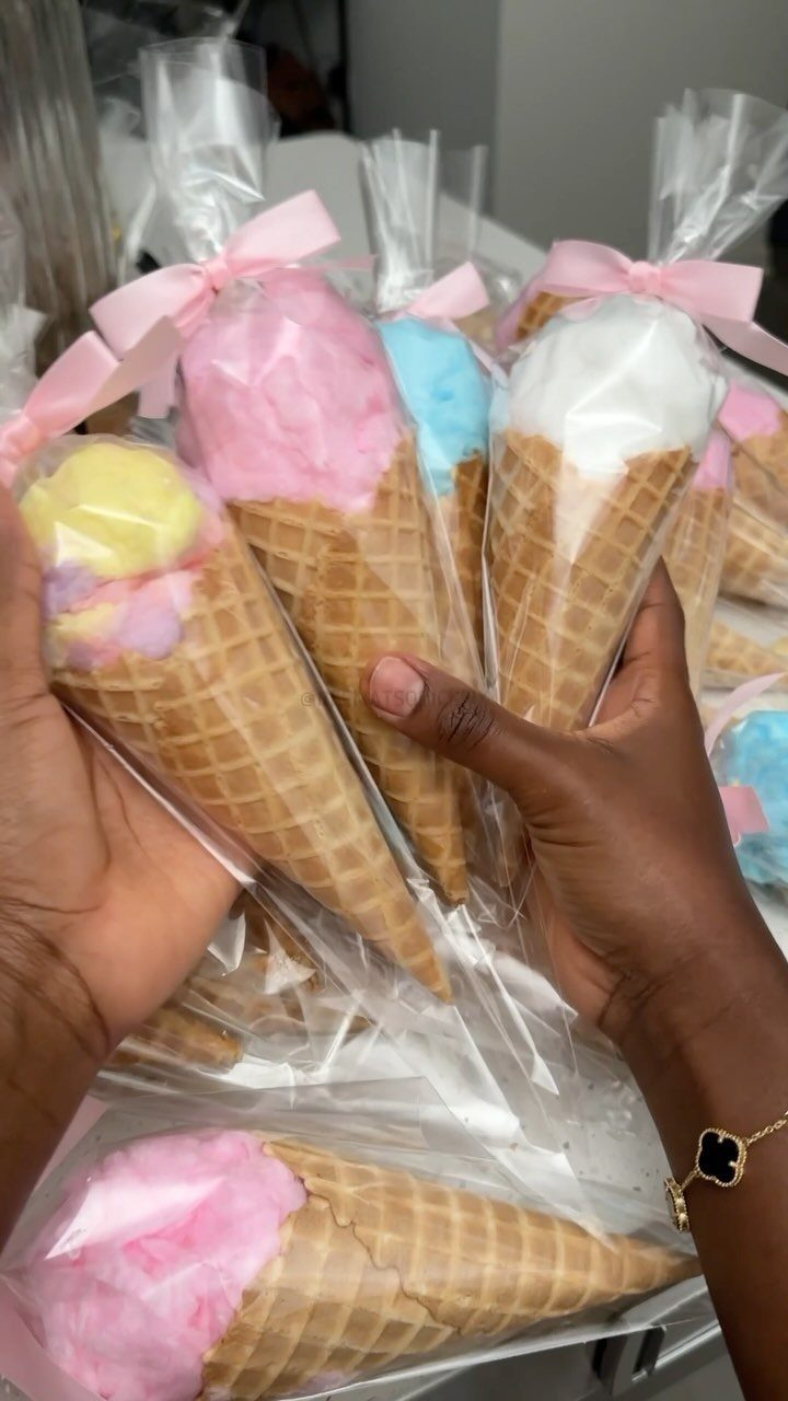 Cotton candy in waffle cones wrapped in plastic with pink ribbons as party favors.
