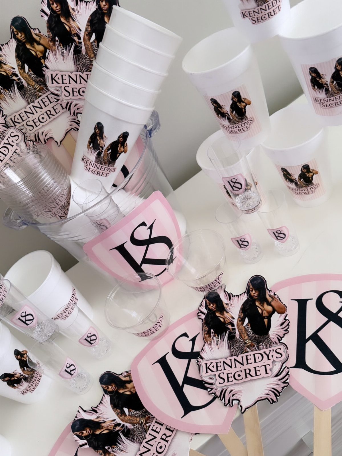 Customized white party cups and shot glasses with personalized branding for an adult birthday.