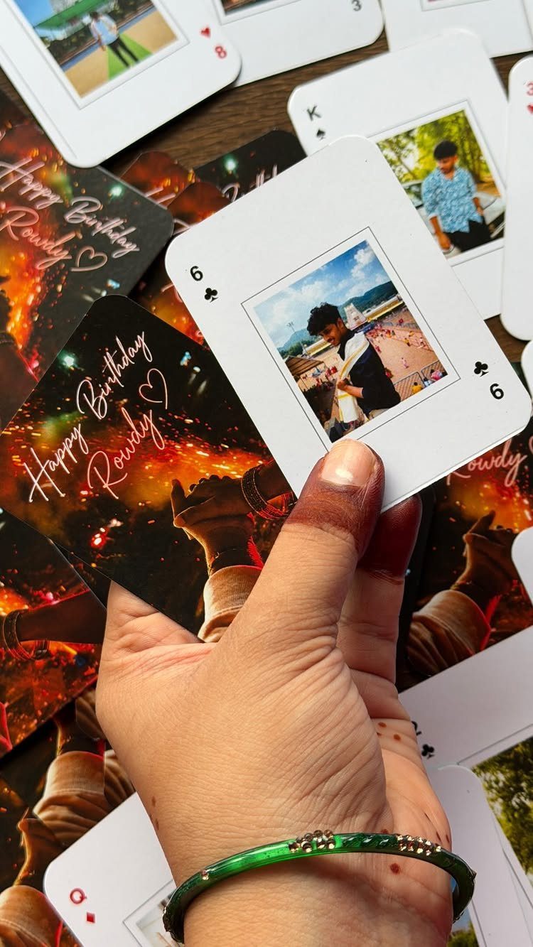 Customized playing cards with personal photos and birthday messages held by a hand.