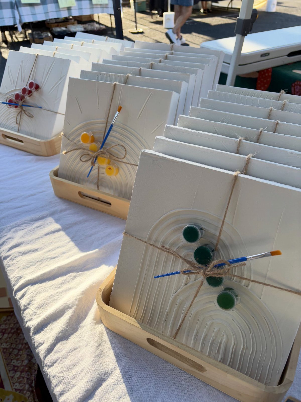 White ceramic tile painting kits with paintbrushes and paint pots tied with twine.