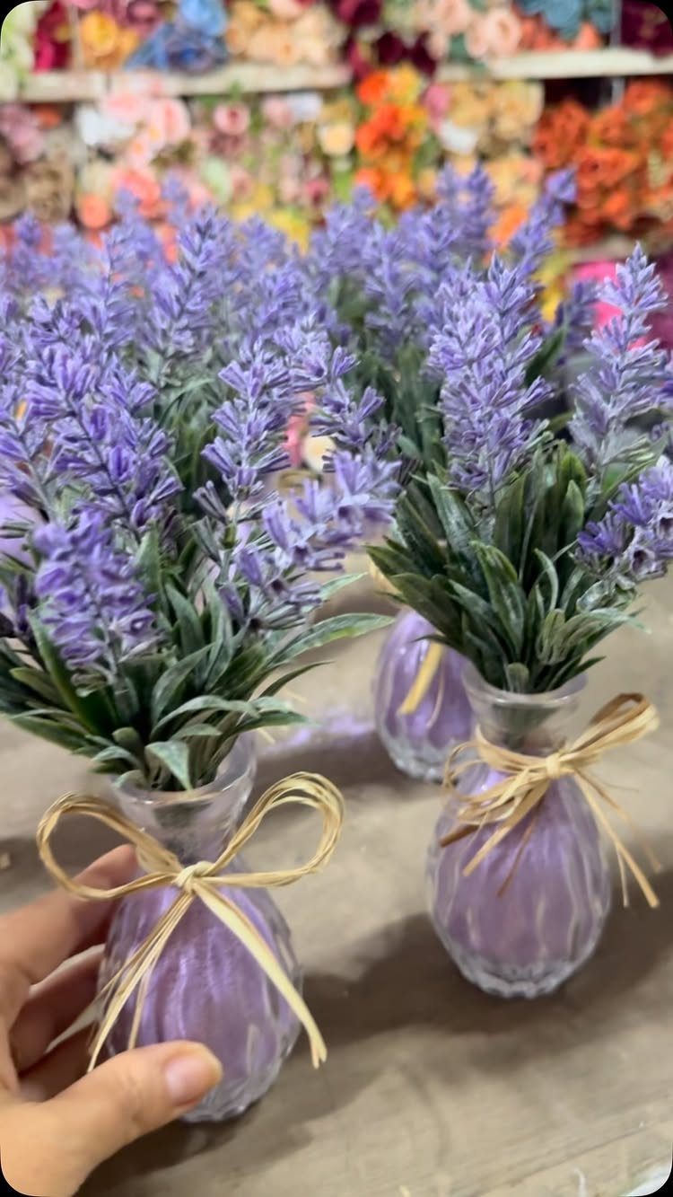 Small purple glass vases with lavender sprigs and raffia bows as party favors.