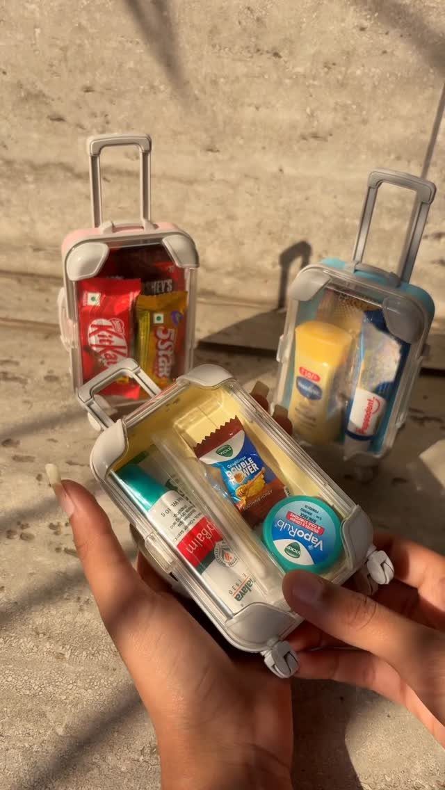 Miniature clear suitcases filled with small candies and toiletries as party favors.