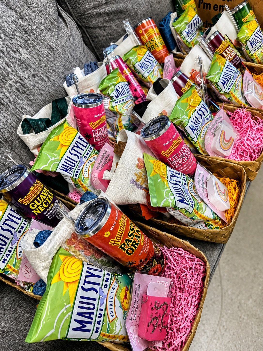 Woven baskets filled with gift bags containing snacks and drinks for party favors.