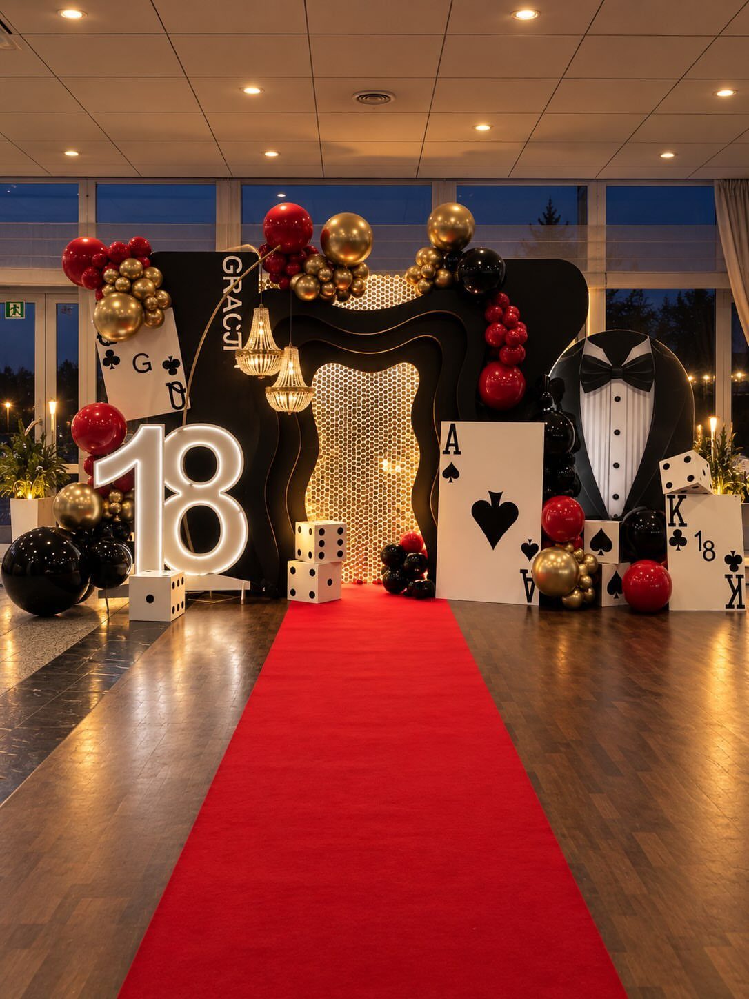 Red carpet entrance with large 18 numbers, casino decorations, and gold and red balloons.