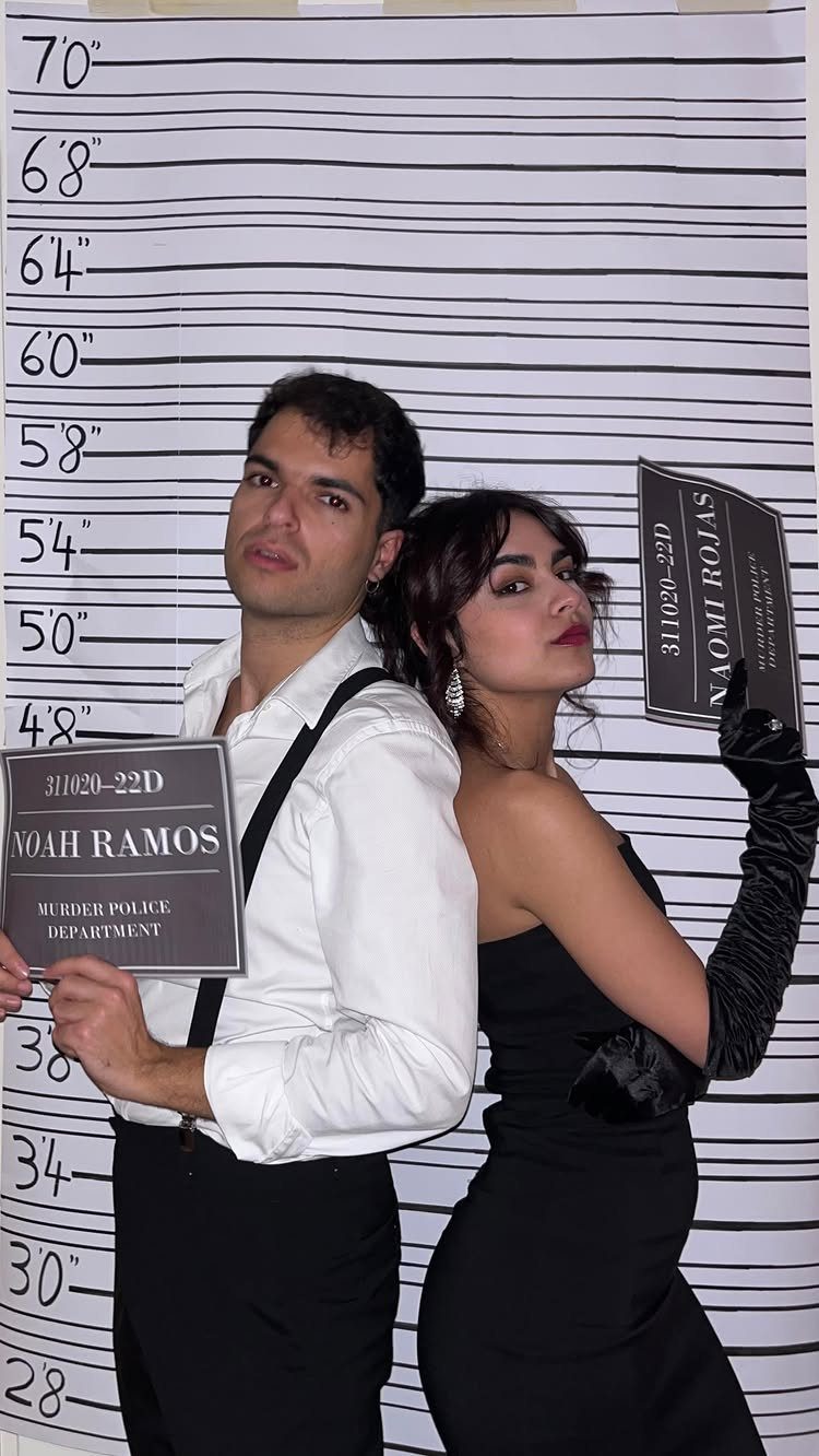 Man and woman posing back-to-back against a police lineup height chart background.