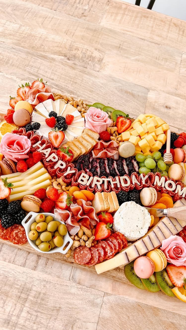 Charcuterie board with meats, cheeses, and fruits featuring Happy Birthday Mom letter decorations