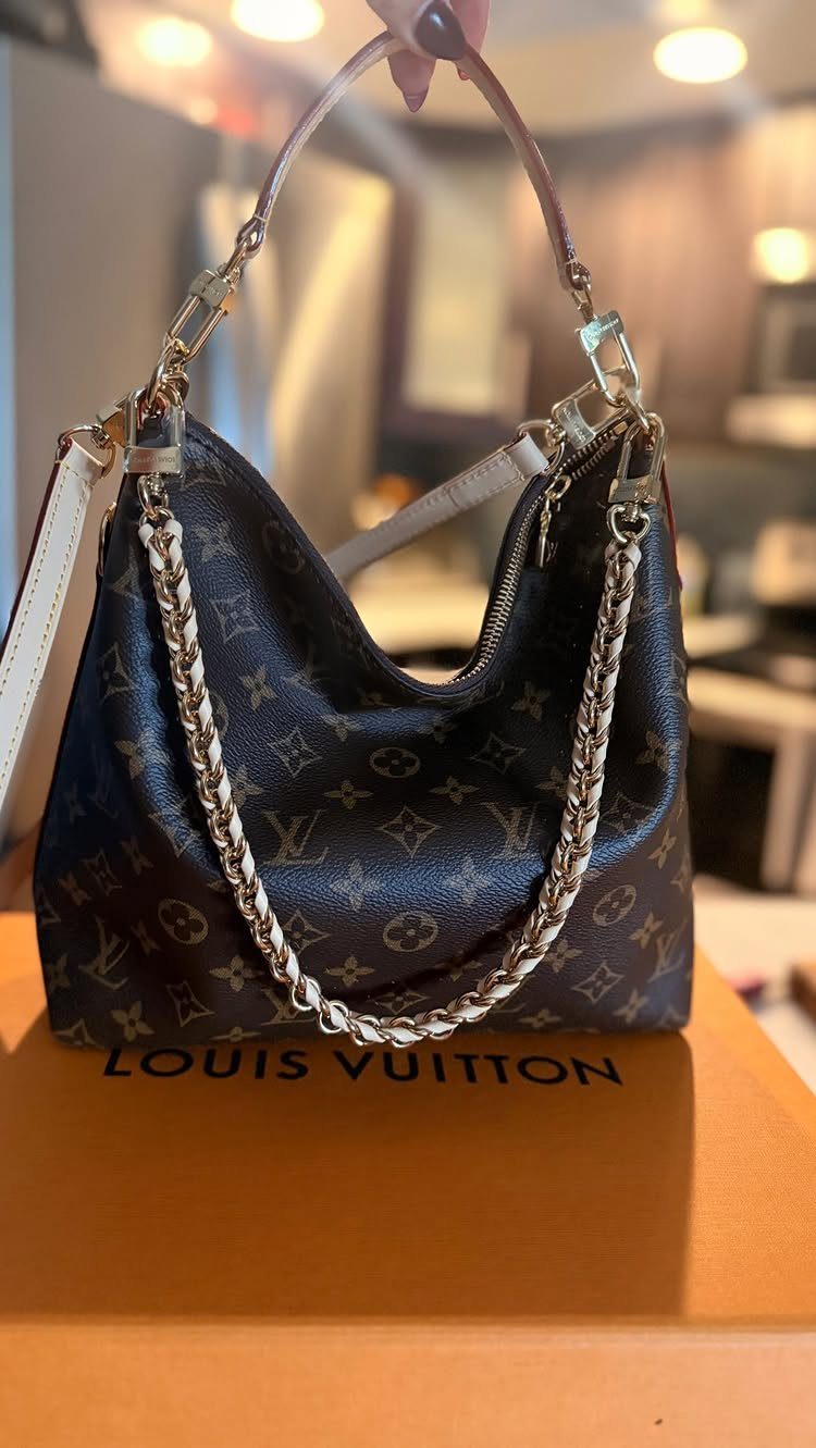 Louis Vuitton monogram handbag resting on an orange branded gift box