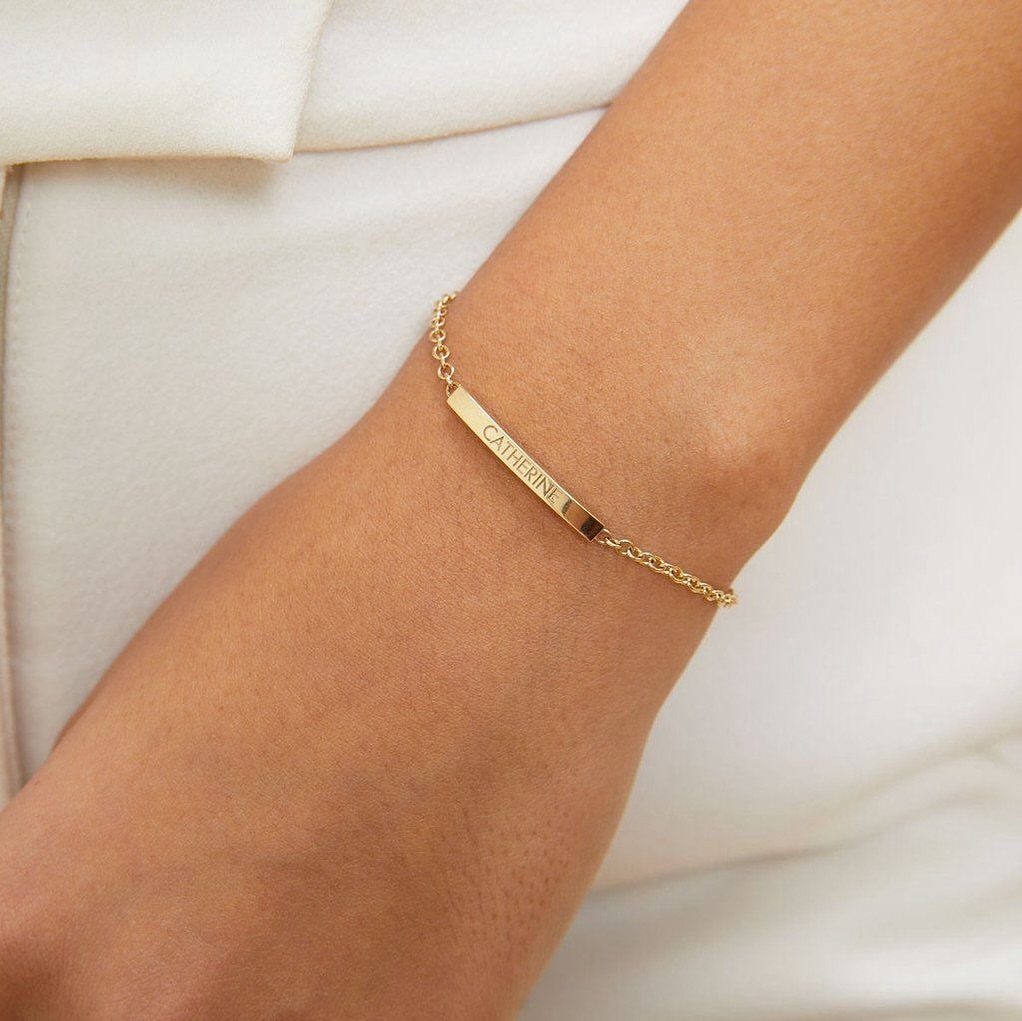 Gold chain bracelet with a rectangular bar engraved with the name Catherine.