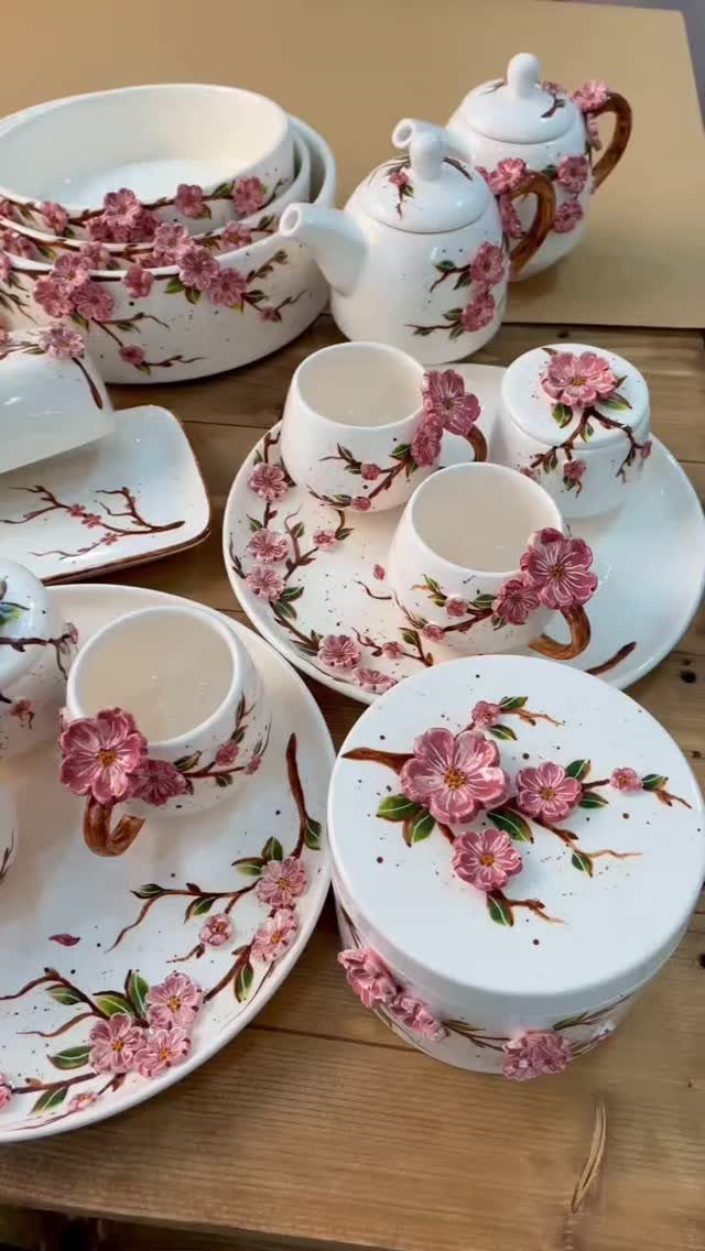 White ceramic tea set with pink cherry blossom floral patterns on wooden table