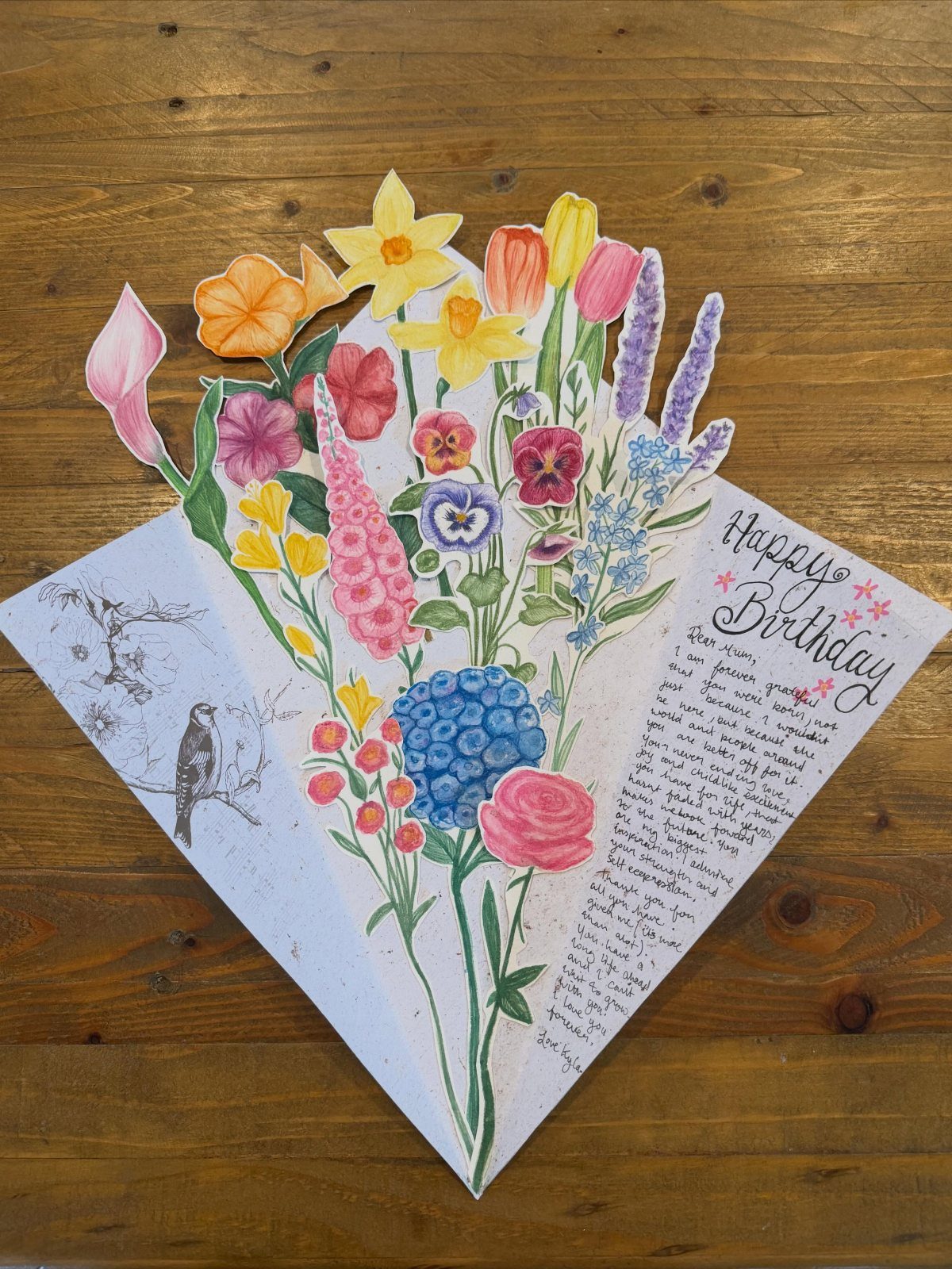 Handmade 3D birthday card with a pop-up flower bouquet on a wooden table