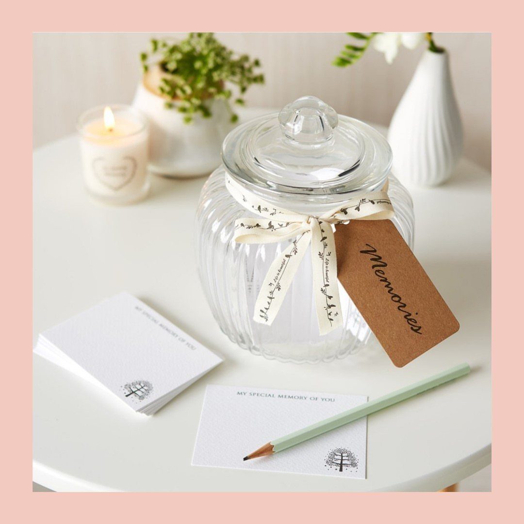 Glass memory jar with a brown tag, note cards, and a pencil.